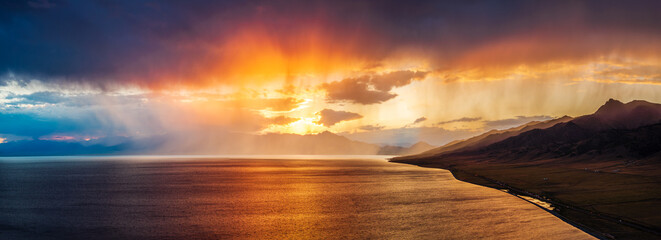 Beautiful Sayram Lake natural landscape at sunset in Xinjiang. Calm lake and mountain with colorful sky clouds scenery. Famous travel destination in China.