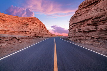 Asphalt road and Yardang landform mountain natural landscape at dusk in Xinjiang, China. Outdoor natural background.