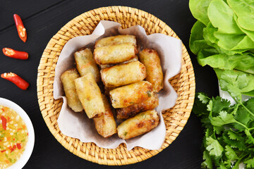Fried spring rolls with sweet chili sauce on a woven basket