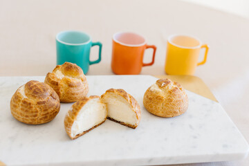 choux cream or cream puff or French profiteroles with fresh cream set on cafe table with antique colored cup