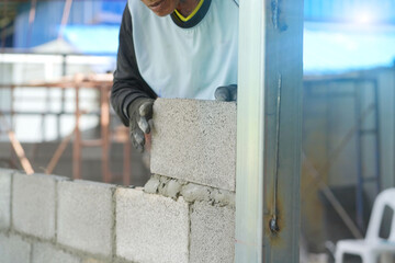 The builder places the block during the construction of the wall