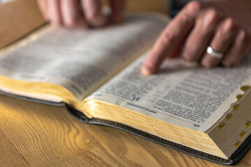 A man reads the Bible. Male hands on the Holy Bible. Close-up of the Bible.