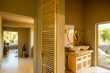 Bathroom interior with natural materials and two stone sinks. Soft sunlight highlights the unique...