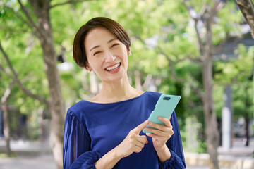 公園でスマホを持つ女性　カメラ目線