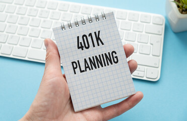 401K Planning text in hand on book note with calculator, pen and smartphone.