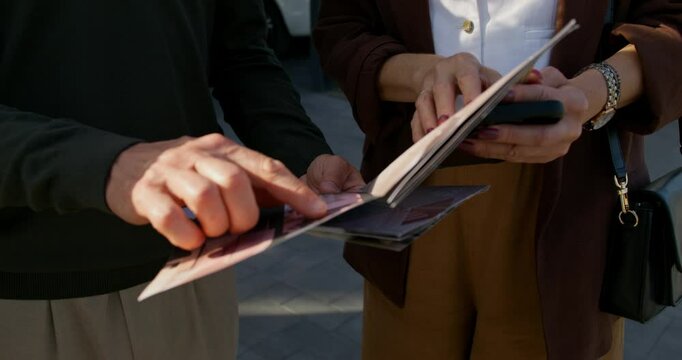 The realtor and the buyers are considering a booklet with a house design project. Close-up of their hands, unrecognizable persons