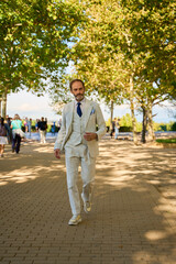 Caucasian man over 50 in striped suit walking confidently in a sunny park