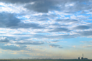 Obraz premium CHP and other plants stand on the shore of the lake in the evening under clouds in the sky