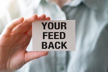 Businesswoman holding a card with Your Feedback text in modern office interior