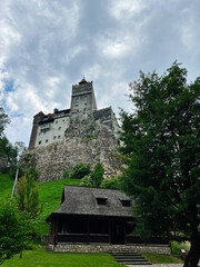 Majestic Bran Castle with lush greenery under a dramatic sky