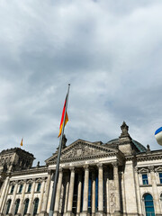 Obraz premium Historical landmark Reichstag building with German flag and cloudy sky