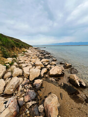 Rocky shoreline of a serene beach under cloudy sky