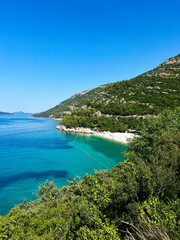 Idyllic beach with clear blue water and lush green hillside.  Beach Veliki Zal, Croatia.