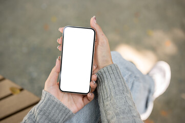 A close-up of a smartphone mockup in a woman's hand, set against a blurred outdoor background.