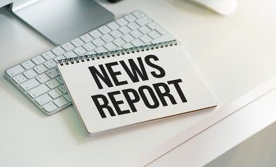 NEWS REPORT text on a paper clipboard with magnifier and keyboard on wooden background