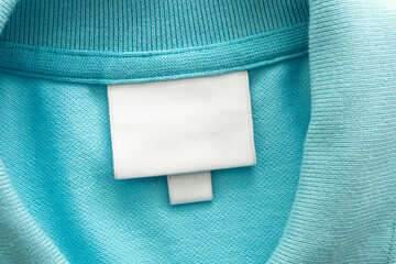 White blank laundry care clothes label on blue shirt fabric background