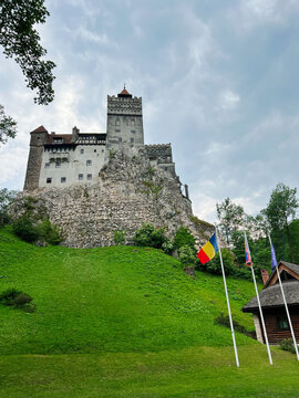 Historic medieval Bran castle on rocky hill with lush green surroundings
