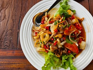 Thai spicy salad with seafood on wooden table, Thai food.