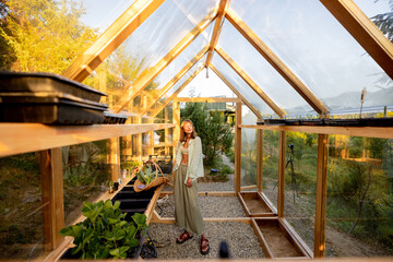 A peaceful morning moment with a woman tending to her plants in a bright wooden greenhouse in the mountains