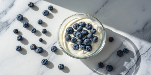 Fresh blueberries on greek yogurt in sunlit marble setting. Horizontal banner, website header.