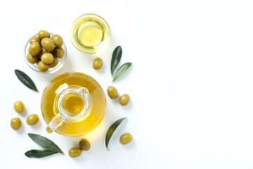 Bottle of fresh olive oil and olives with leaves on white background