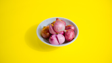 red onion in white bowl on yellow background 