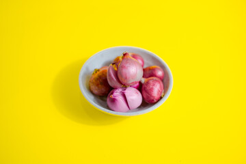 red onion in white bowl on yellow background 