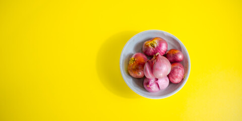 red onion in white bowl on yellow background 
