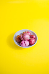 red onion in white bowl on yellow background 