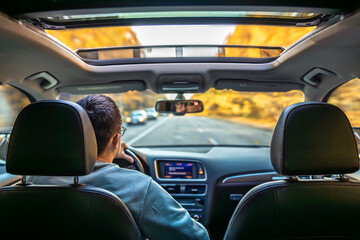 Driving the modern car on asphalt road. A young man drives a car.