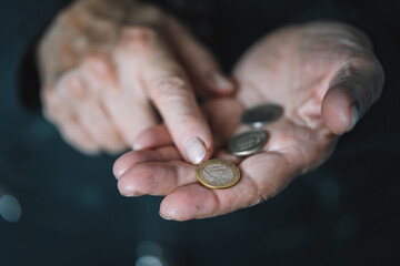Defocused view to elderly woman counts metal coins, wrinkled female hands close up. Concept of...