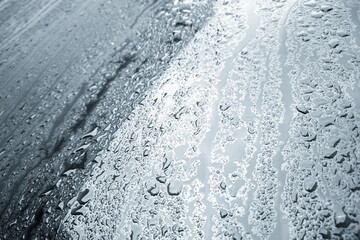Obraz premium rain water drops on a bonnet of a black car during rainy day