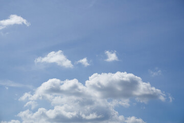 Obraz premium Bright blue sky with fluffy white clouds, perfect for backgrounds or nature themes. Clear and serene atmosphere, ideal for creative projects or designs.