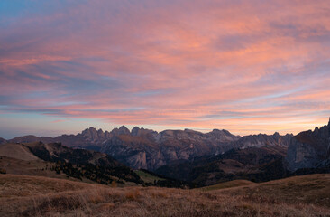 Sunrise orange clouds above stunning Dolomite mountains