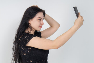 Cute young brunette girl making selfie on a white background