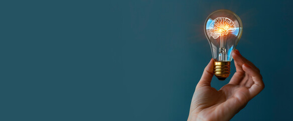 Human hands holding light bulb with a glowing brain inside on plain blue background. Creative concept idea, brainstorming, puzzle, business, design, brainstorming
