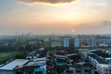 Sunset over the vibrant cityscape filled with rooftops and distant silhouettes