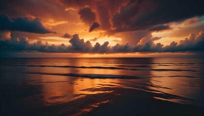 Fototapeta premium Una espectacular puesta de sol sobre un océano en calma, con vibrantes nubes de color naranja, amarillo y azul reflejándose en el agua tranquila. El sol se pone detrás de las nubes, creando una impres