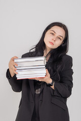 Young cute brunette girl with a stack of books on a white background. Copy space