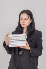Fototapeta premium Young cute brunette girl with a stack of books on a white background. Copy space