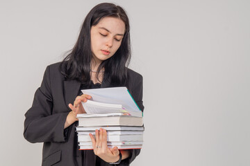 Fototapeta premium Young cute brunette girl with a stack of books on a white background. Copy space