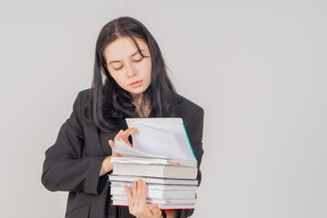 Fototapeta premium Young cute brunette girl with a stack of books on a white background. Copy space