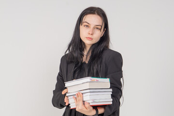 Young cute brunette girl with a stack of books on a white background. Copy space