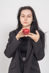 Young cute brunette girl with a red apple on a white background. Copy space