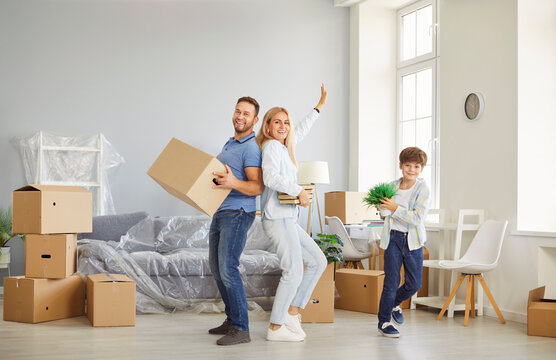Family with son celebrating moving into new home by dancing together. This joyful moment of real estate ownership and relocation brings fun and excitement to their shared experience.