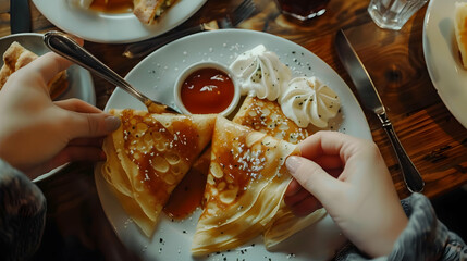 Person eating crepes without filling. Various sauces around the pancake.