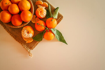 Fresh juicy tangerines with green leaves placed on a rustic burlap cloth, illuminated by warm...
