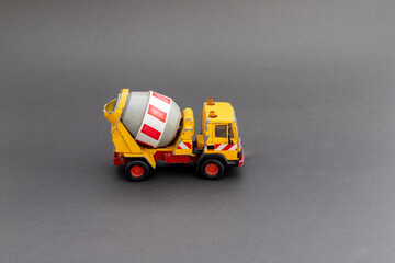 Yellow cement mixer truck model on grey background with copy space for text