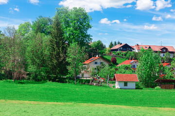 Picturesque rural scene in Bavaria, with lush green fields and several houses featuring red tiled roofs. Idyllic nature of the Bavarian countryside landscape in Germany