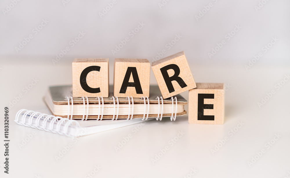 Fototapete text care on wooden block with notebook on gray background.